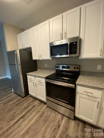 a kitchen with granite countertop white cabinets and black appliances