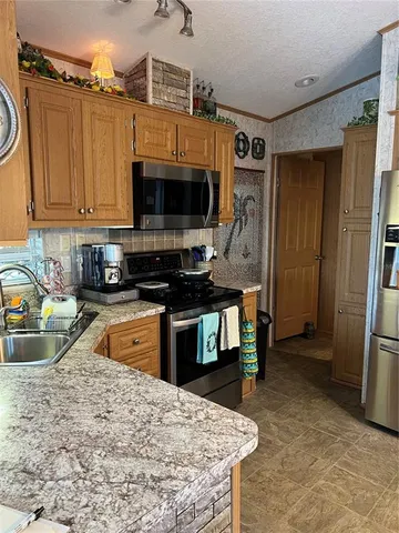 a kitchen with stainless steel appliances granite countertop a refrigerator a stove top oven a sink and dishwasher