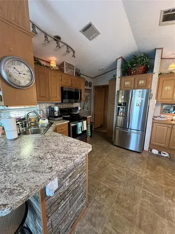 a kitchen with stainless steel appliances granite countertop a sink a stove and a refrigerator