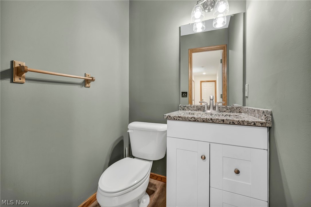 9842 Johnnycake Ridge Road Mentor, OH 44060 - Photo 15 of 40 Powder room with a white single-sink vanity, speckled countertop, rectangular mirror, and three-light fixture