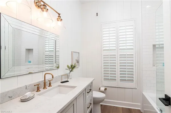 a bathroom with a granite countertop sink toilet a large mirror and a tub