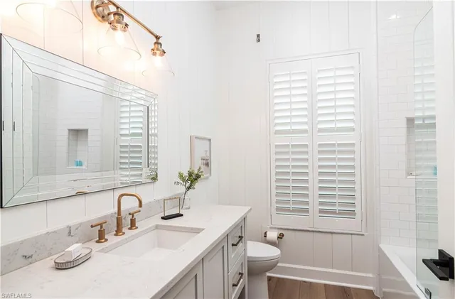a bathroom with a granite countertop sink toilet a large mirror and a tub