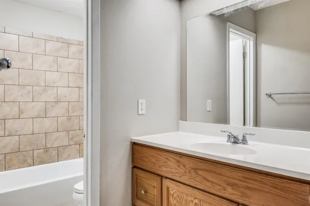 a bathroom with a granite countertop sink a mirror and a bathtub