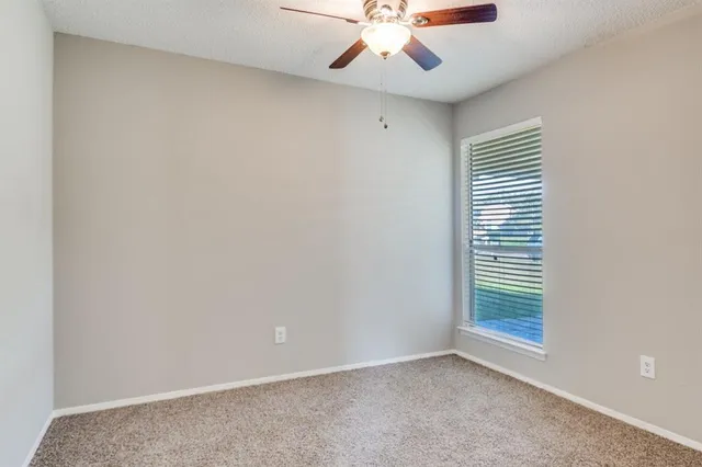an empty room with a window and a fan