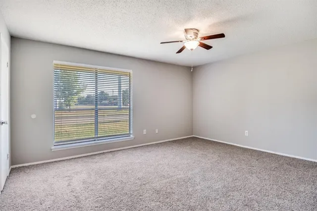 an empty room with windows and fan