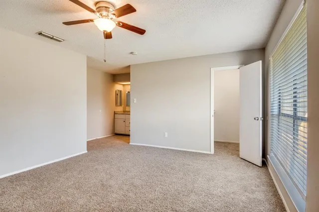 an empty room with chandelier fan and windows