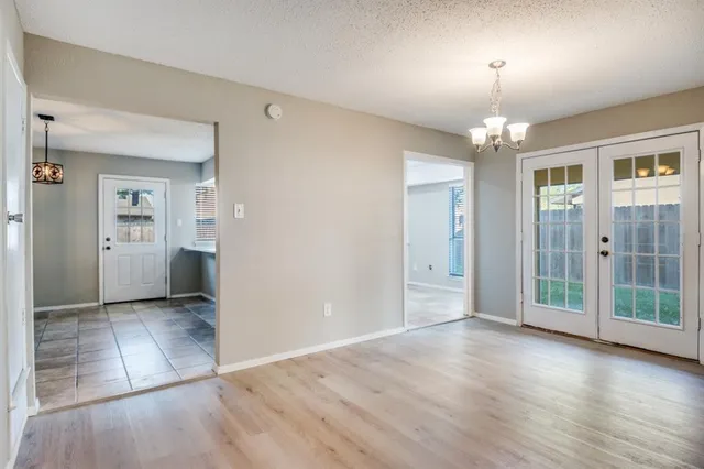 an empty room with wooden floor chandelier and windows