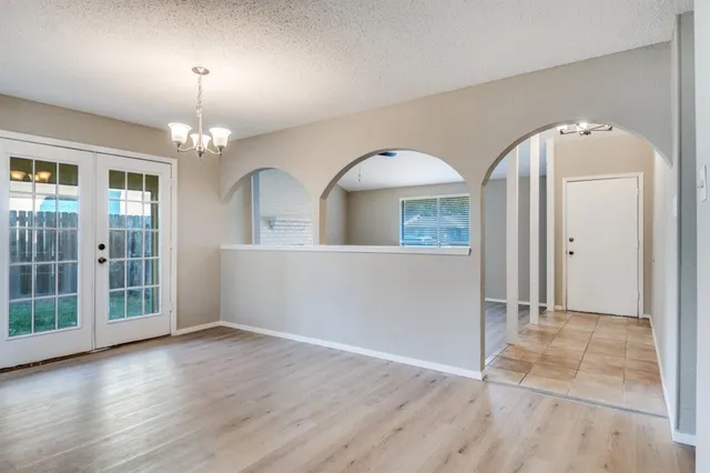 an empty room with wooden floor mirror and windows