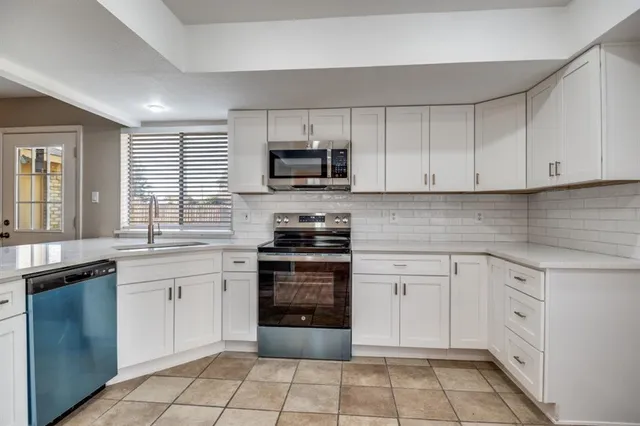 a kitchen with cabinets stainless steel appliances and a window