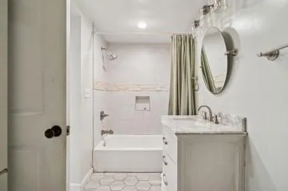 a bathroom with a granite countertop sink a mirror and a bathtub