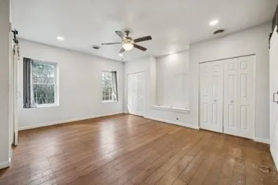 a view of an empty room with a window and wooden floor