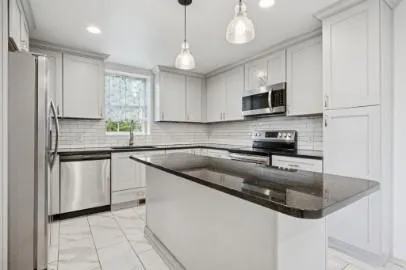 a kitchen with stainless steel appliances granite countertop a sink a stove a microwave and cabinets
