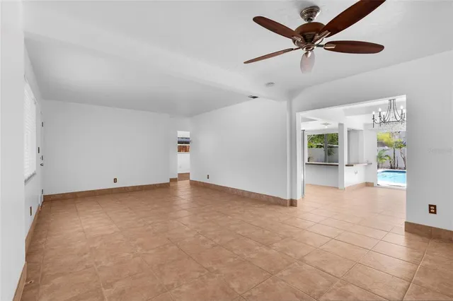 an empty room with chandelier fan and windows
