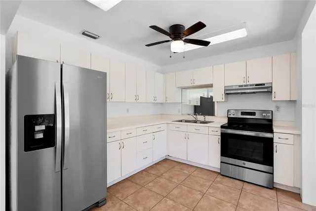 a kitchen with stainless steel appliances granite countertop a refrigerator a sink a stove and white cabinets