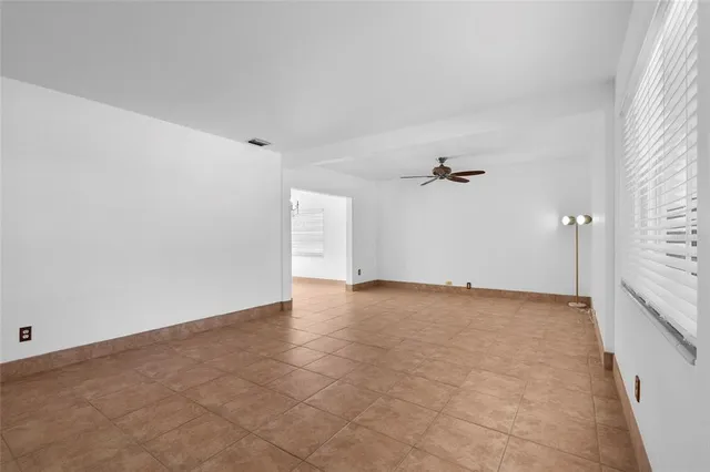 an empty room with chandelier fan and windows
