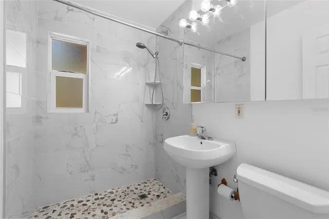 a bathroom with a sink a toilet and shower