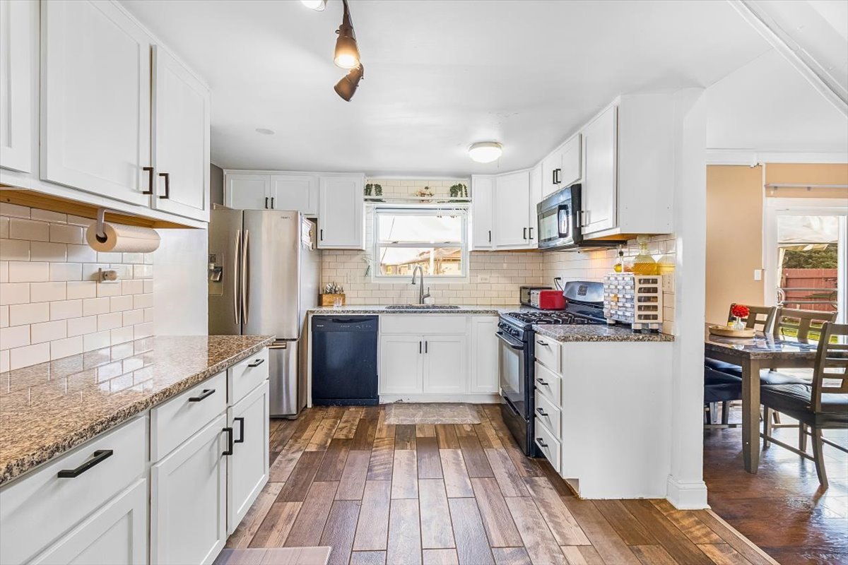 6881 Hickory Street Hanover Park, IL 60133 - Photo 14 of 23 a kitchen with stainless steel appliances granite countertop a refrigerator a stove top oven a sink dishwasher and white cabinets with wooden floor