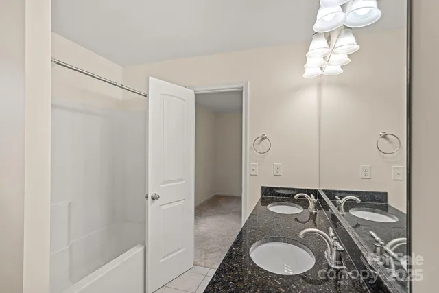 a bathroom with a granite countertop double vanity sink and mirror