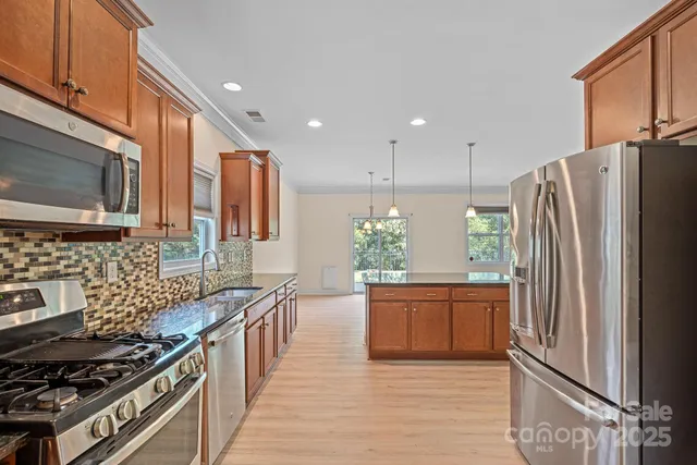 a kitchen with stainless steel appliances granite countertop a refrigerator a stove and a wooden cabinets