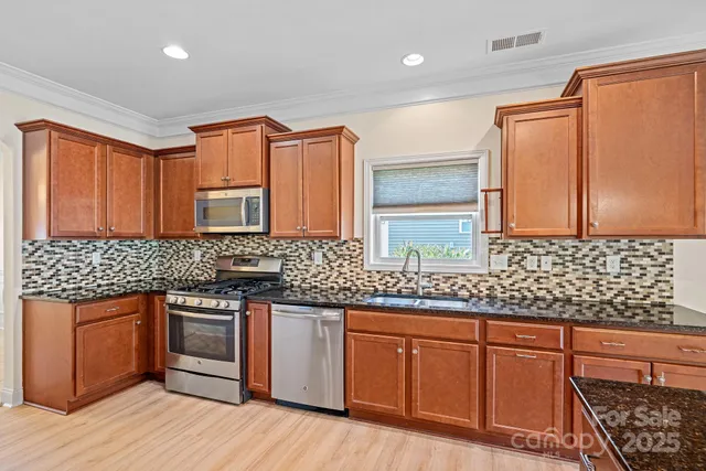 a kitchen with stainless steel appliances granite countertop a sink a stove cabinets and wooden floor
