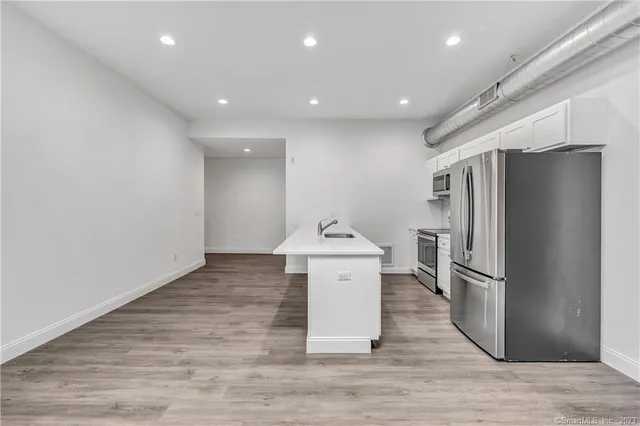 a kitchen with stainless steel appliances a refrigerator and wooden floor