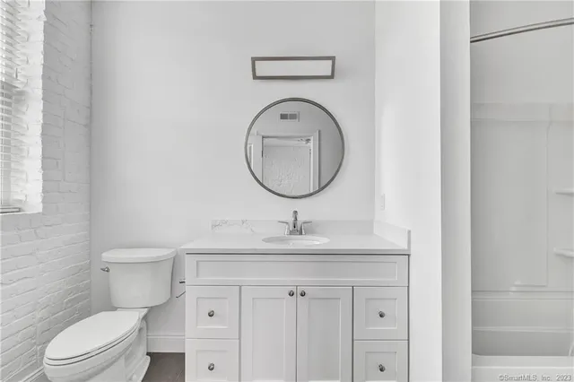 a bathroom with a granite countertop toilet sink and mirror