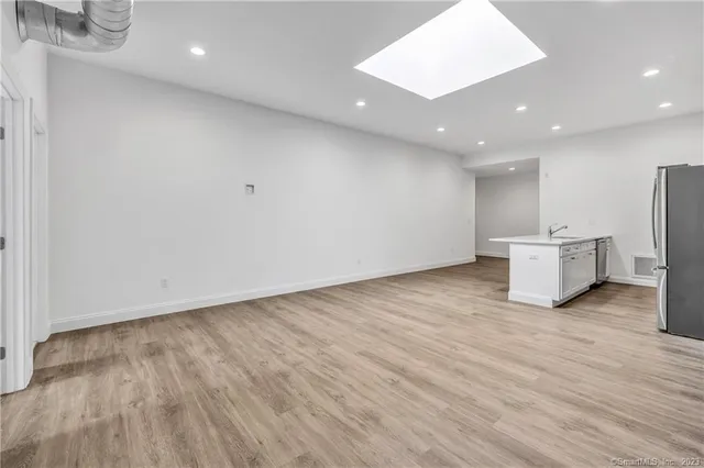 a view of an empty room with wooden floor and white walls