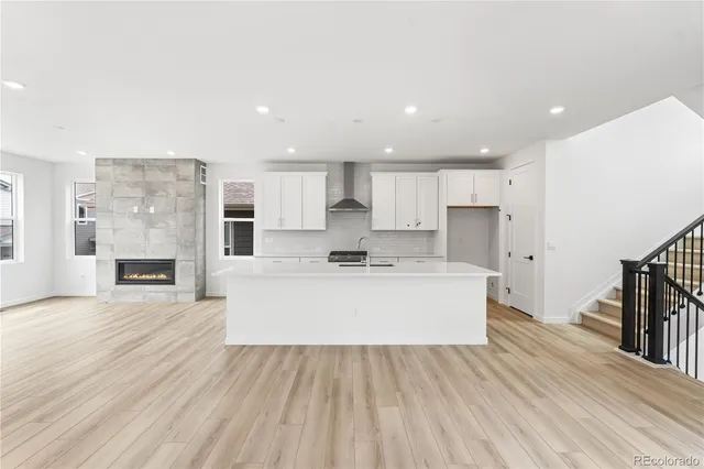 a large white kitchen with kitchen island a sink wooden floor and a fireplace
