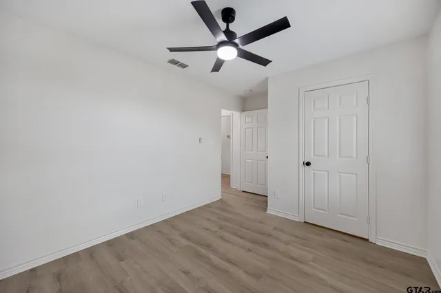 an empty room with wooden floor and ceiling fan