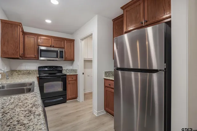 a kitchen with granite countertop stainless steel appliances and wooden cabinets
