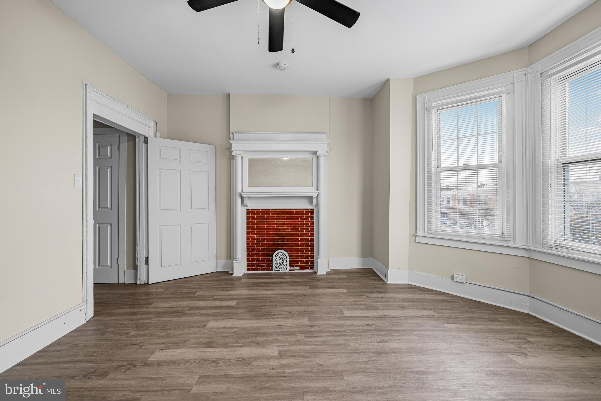 5723 Spruce Street, Unit 2 Philadelphia, PA 19139 - Photo 5 of 16 an empty room with wooden floor chandelier fan and windows