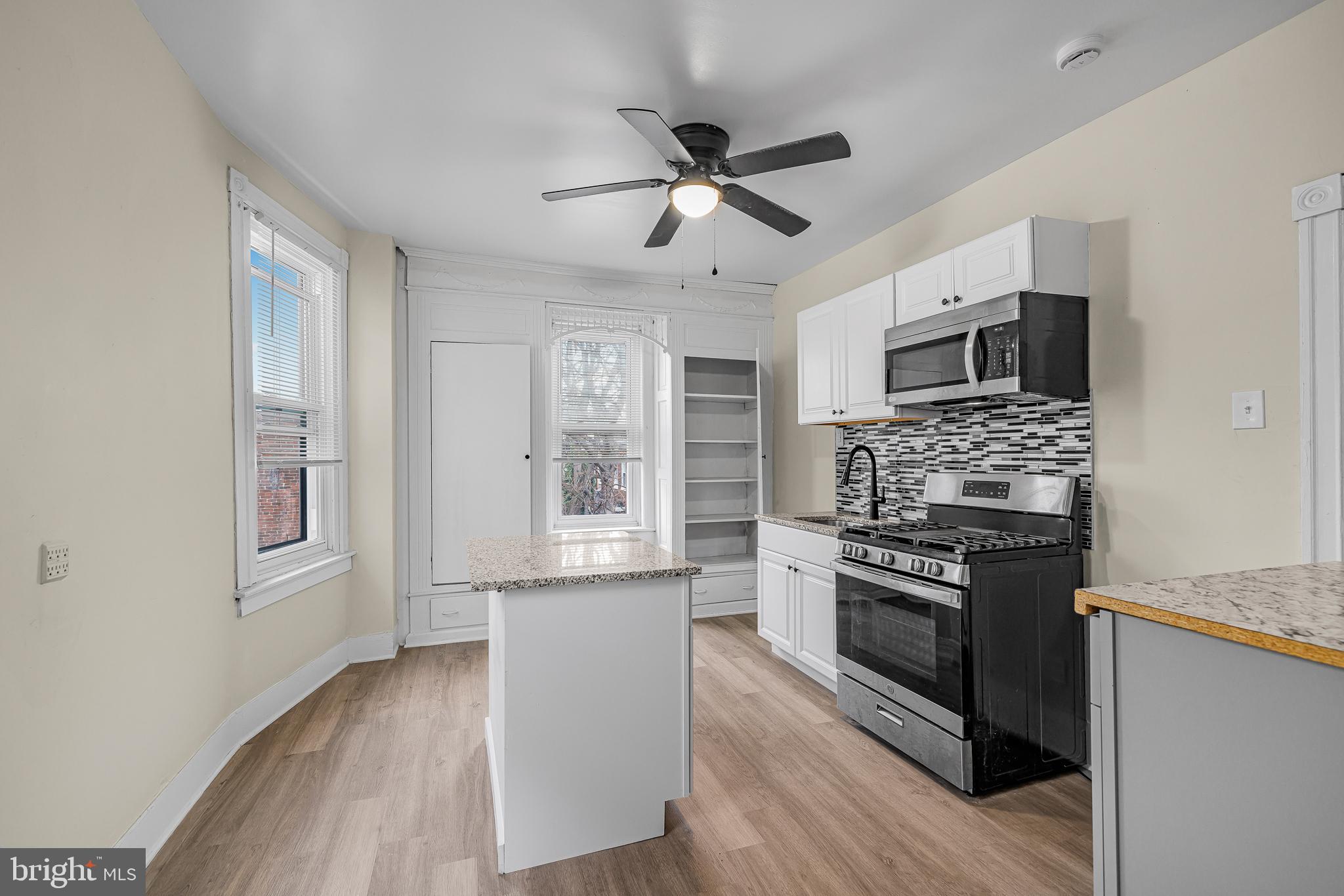 5723 Spruce Street, Unit 2 Philadelphia, PA 19139 - Photo 7 of 16 a kitchen with granite countertop a stove cabinets and wooden floor
