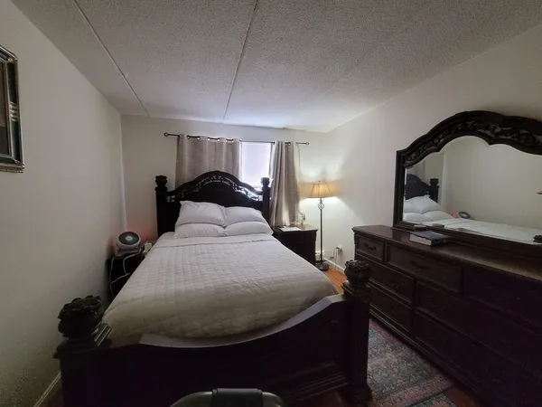a bedroom with a bed and a lamp on dresser