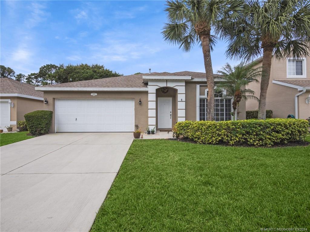 2432 Southeast Springtree Place Stuart, FL 34997 - Photo 1 of 24 a front view of a house with a garden