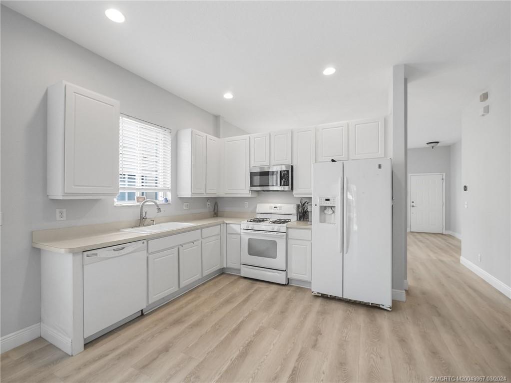 2432 Southeast Springtree Place Stuart, FL 34997 - Photo 11 of 24 a kitchen with white cabinets and white appliances