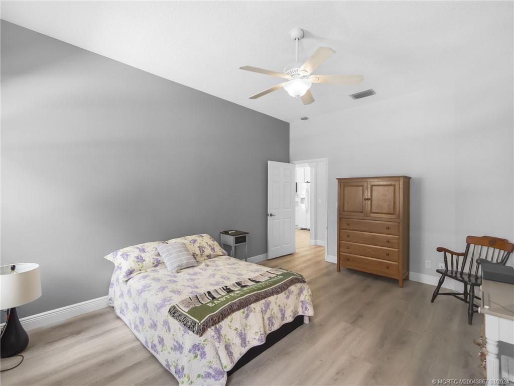 2432 Southeast Springtree Place Stuart, FL 34997 - Photo 15 of 24 a bedroom with a bed and a chandelier