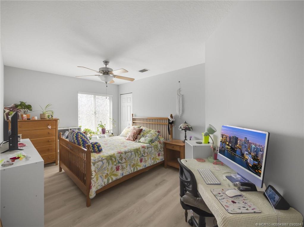 2432 Southeast Springtree Place Stuart, FL 34997 - Photo 17 of 24 a bedroom with furniture and a chandelier