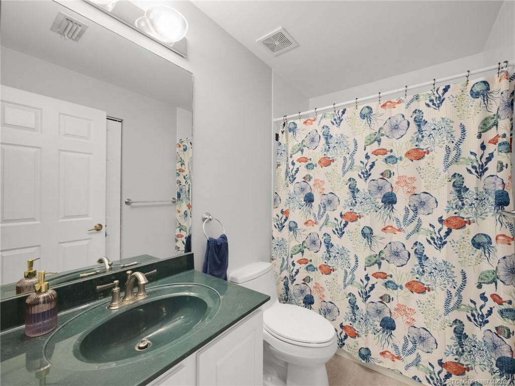 2432 Southeast Springtree Place Stuart, FL 34997 - Photo 18 of 24 a bathroom with a granite countertop sink a toilet and a mirror