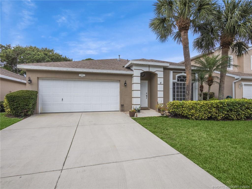 2432 Southeast Springtree Place Stuart, FL 34997 - Photo 2 of 24 a front view of a house with a yard and garage