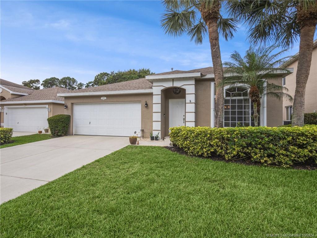 2432 Southeast Springtree Place Stuart, FL 34997 - Photo 3 of 24 a front view of a house with a garden
