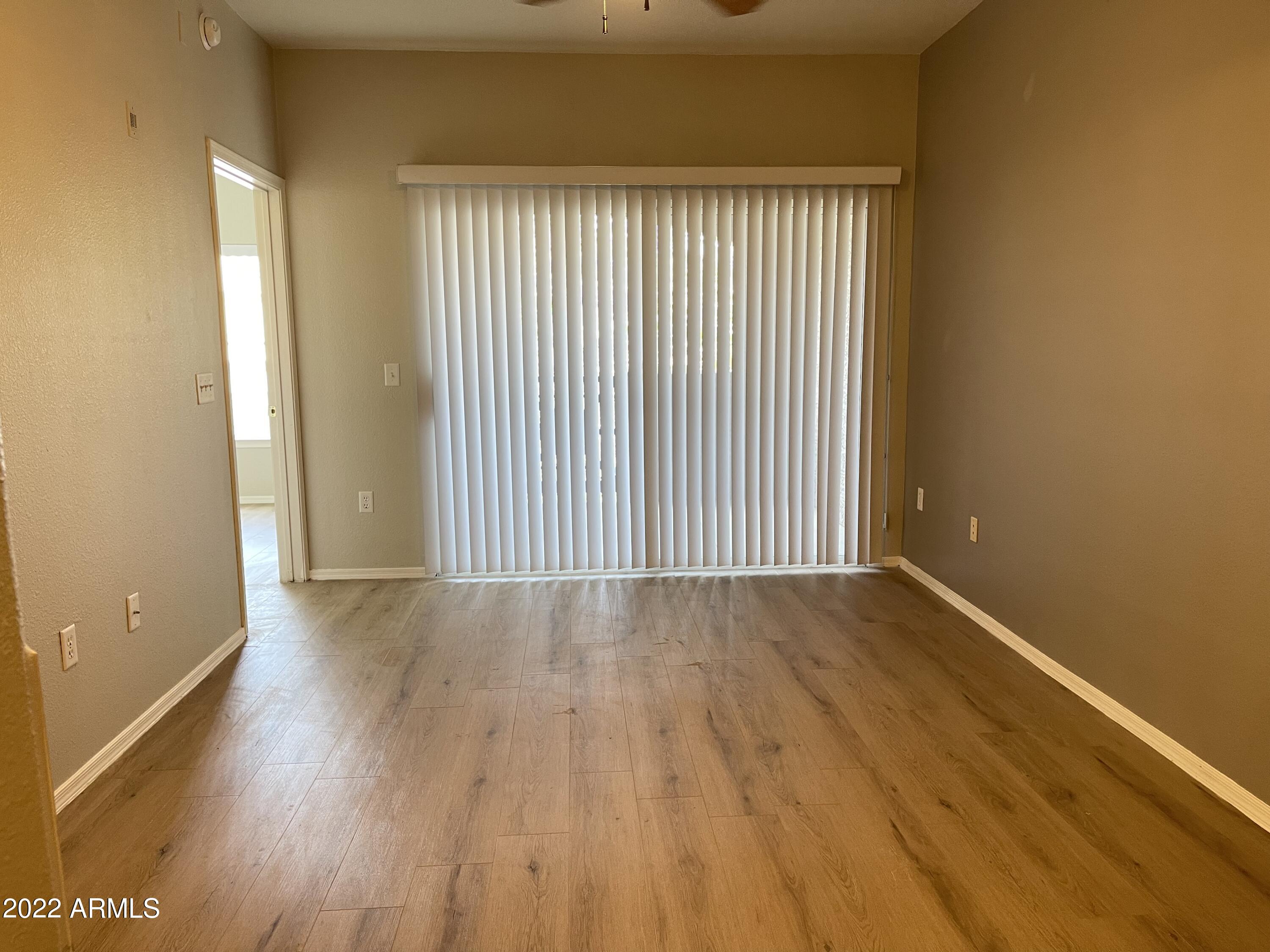 3236 East Chandler Boulevard, Unit 2093 Phoenix, AZ 85048 - Photo 11 of 28 an empty room with wooden floor and windows