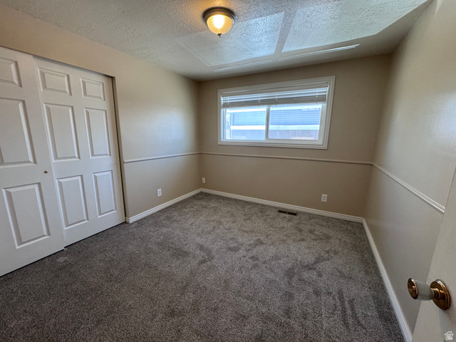 2182 West 5600th Street South Roy, UT 84067 - Photo 6 of 11 Carpeted room featuring a white-trimmed window, a dual-door closet with panel detailing, and neutral wall tones with chair rail molding