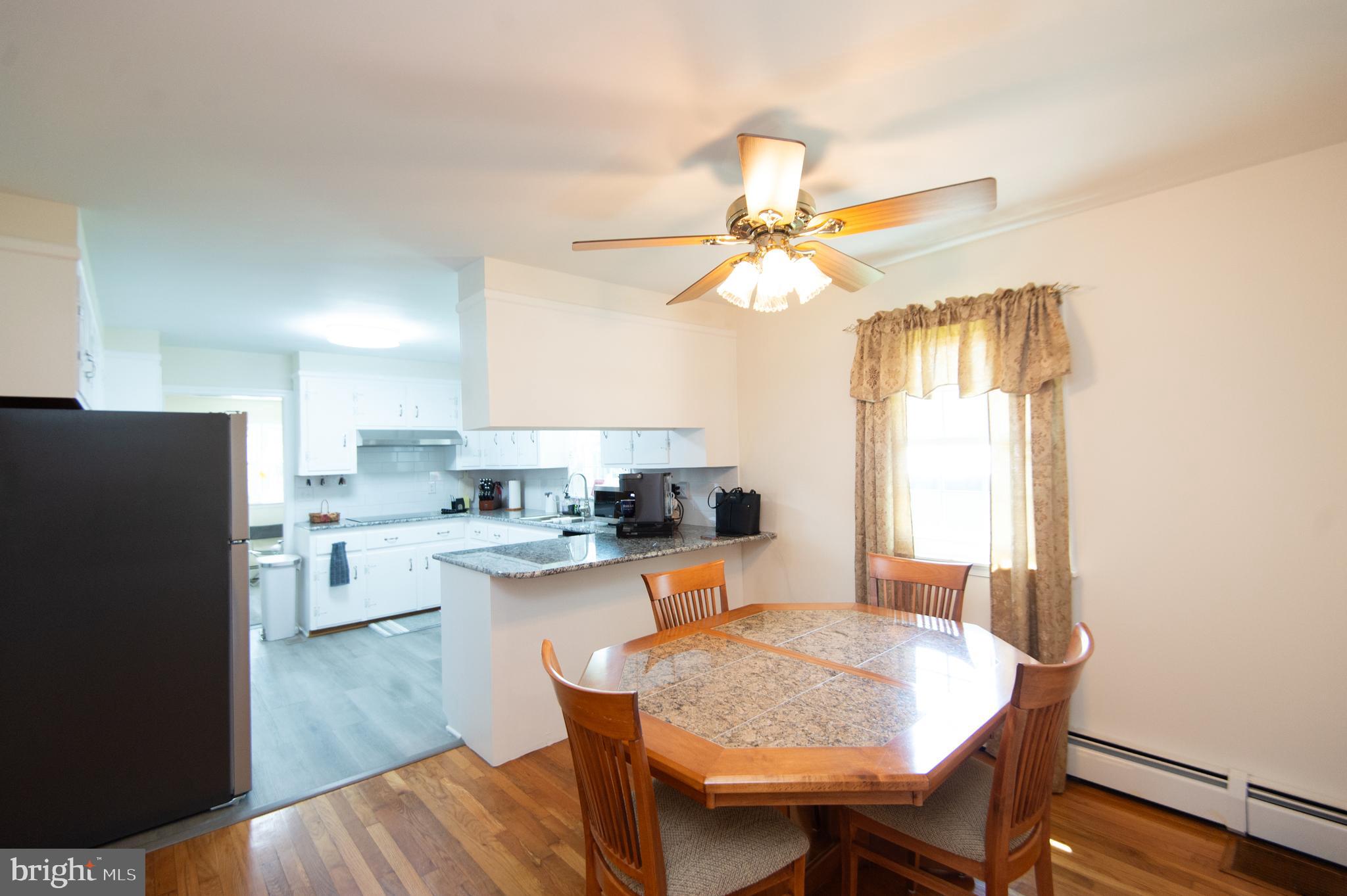 8 West Liberty Street Ridgely, MD 21660 - Photo 13 of 55 a dining room with granite countertop a refrigerator a stove a sink dishwasher a dining table and chairs with wooden floor