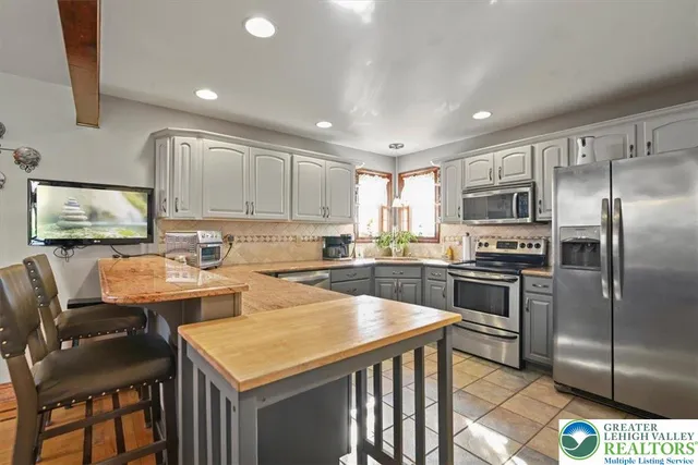a kitchen with stainless steel appliances granite countertop a sink a stove a refrigerator cabinets and chairs