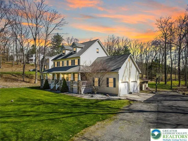 a front view of a house with a garden and trees