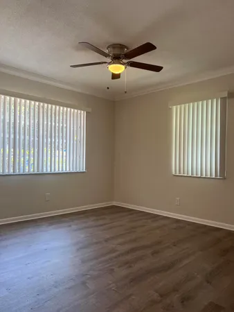 a view of an empty room with wooden floor and window