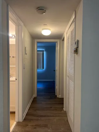 a view of a hallway with wooden floor and closet