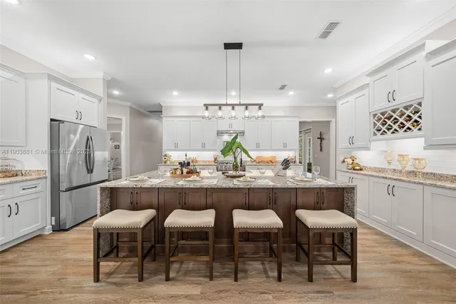 a kitchen with center island wooden floor and stainless steel appliances