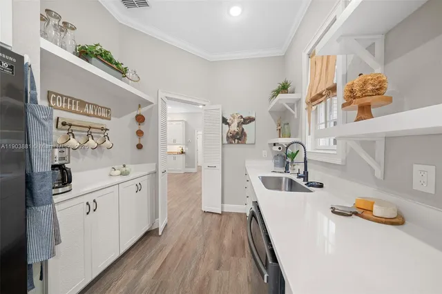 a large white kitchen with a lot of counter space and wooden floor