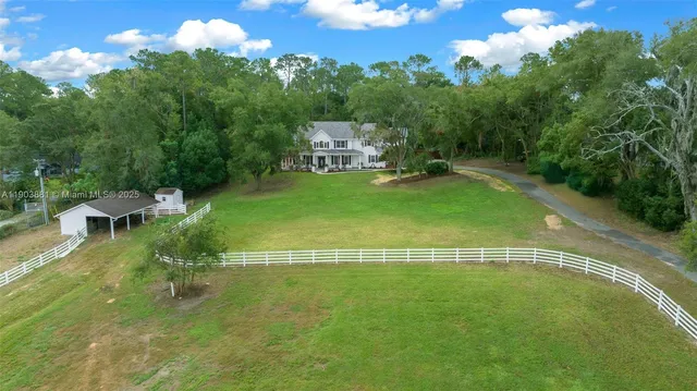a view of a swimming pool with lawn chairs with plants and trees